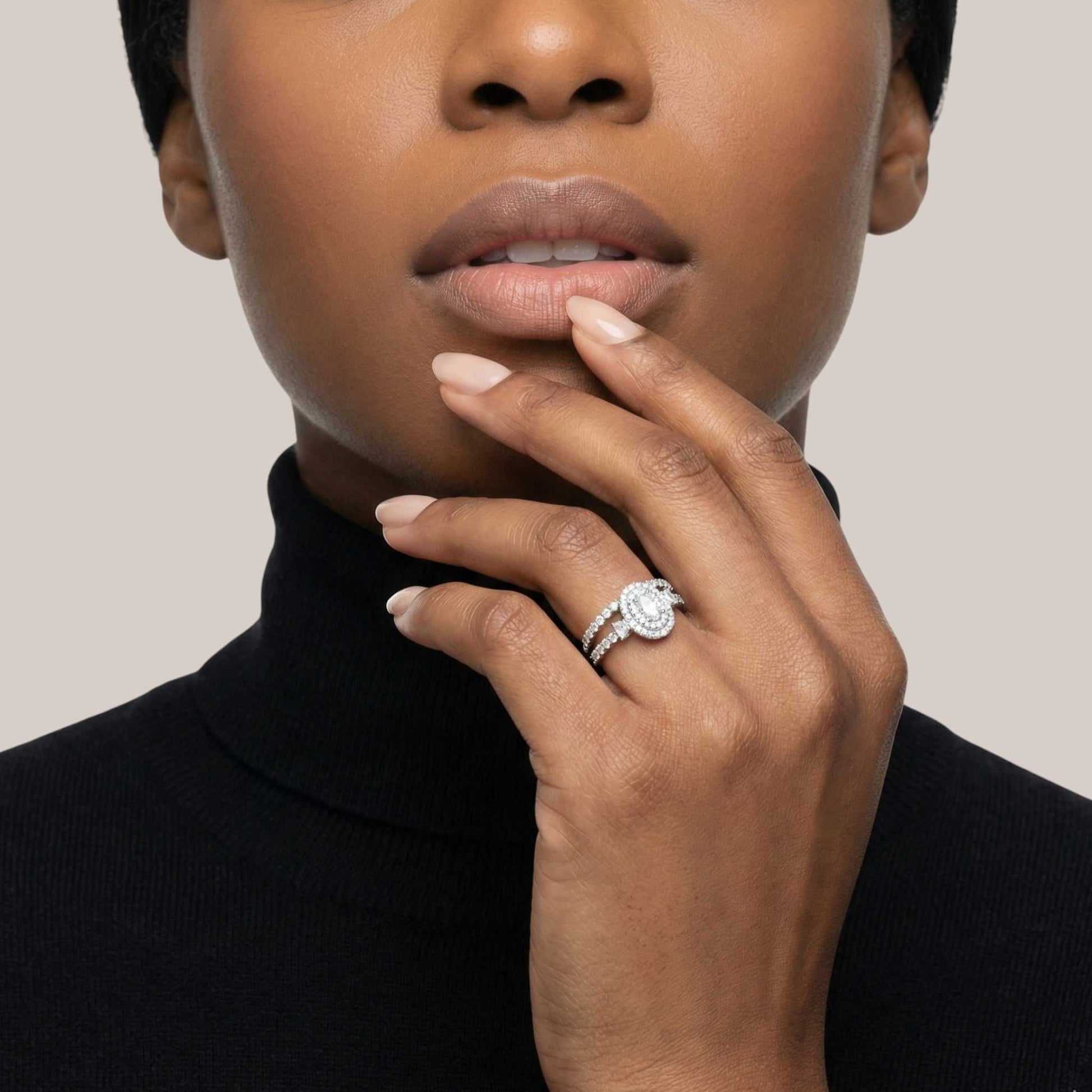 Close-up of a person wearing a diamond ring on a neutral background