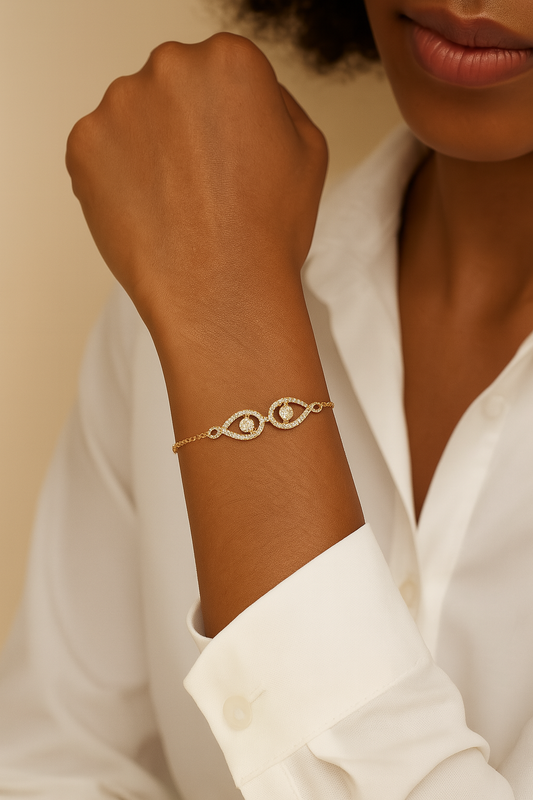 Gold bracelet with eye design on a wrist, wearing a white shirt.