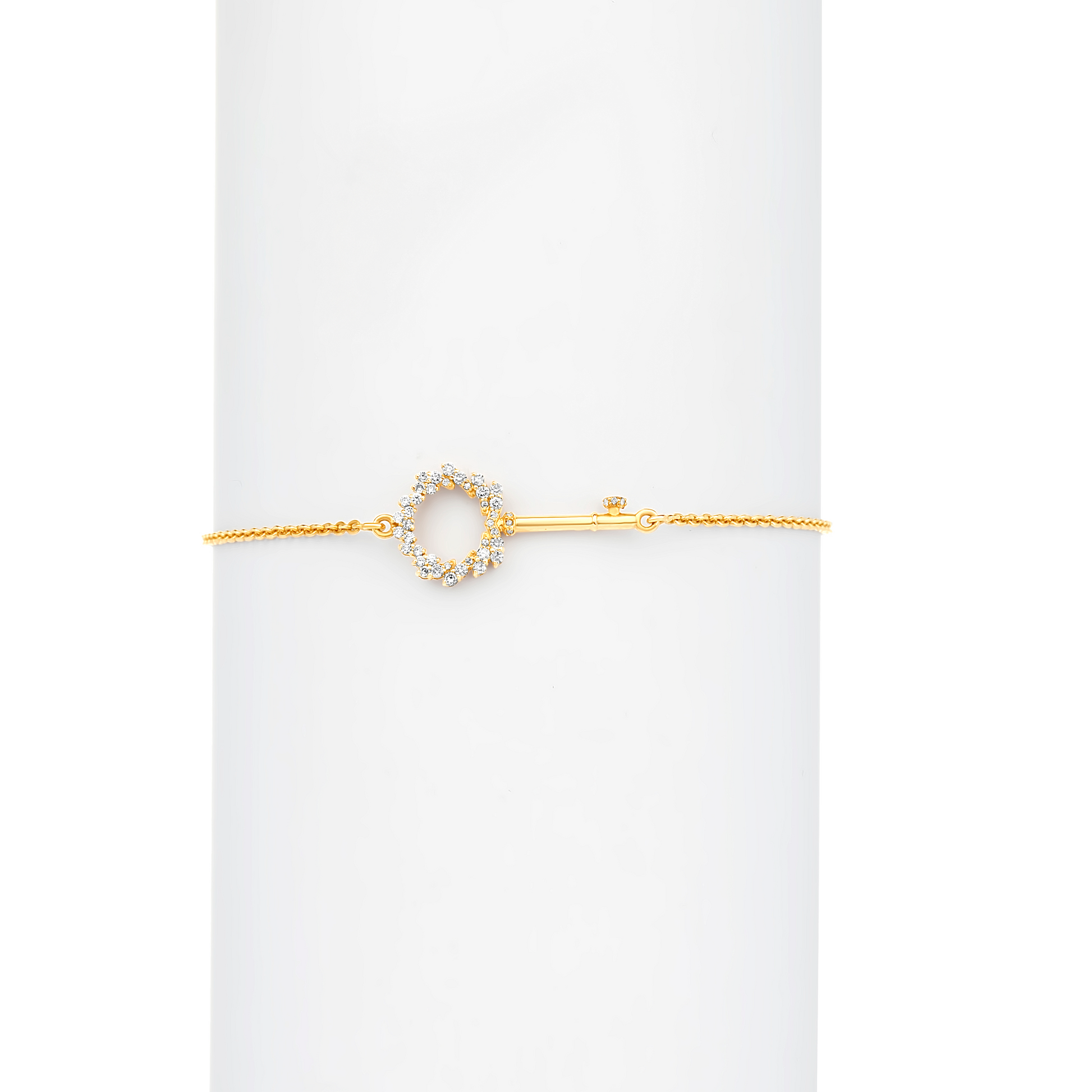 An 18K gold bracelet with a solid pattern, featuring a central diamond-accented charm.