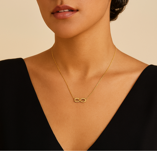 Woman wearing a gold necklace with an infinity symbol against a beige background