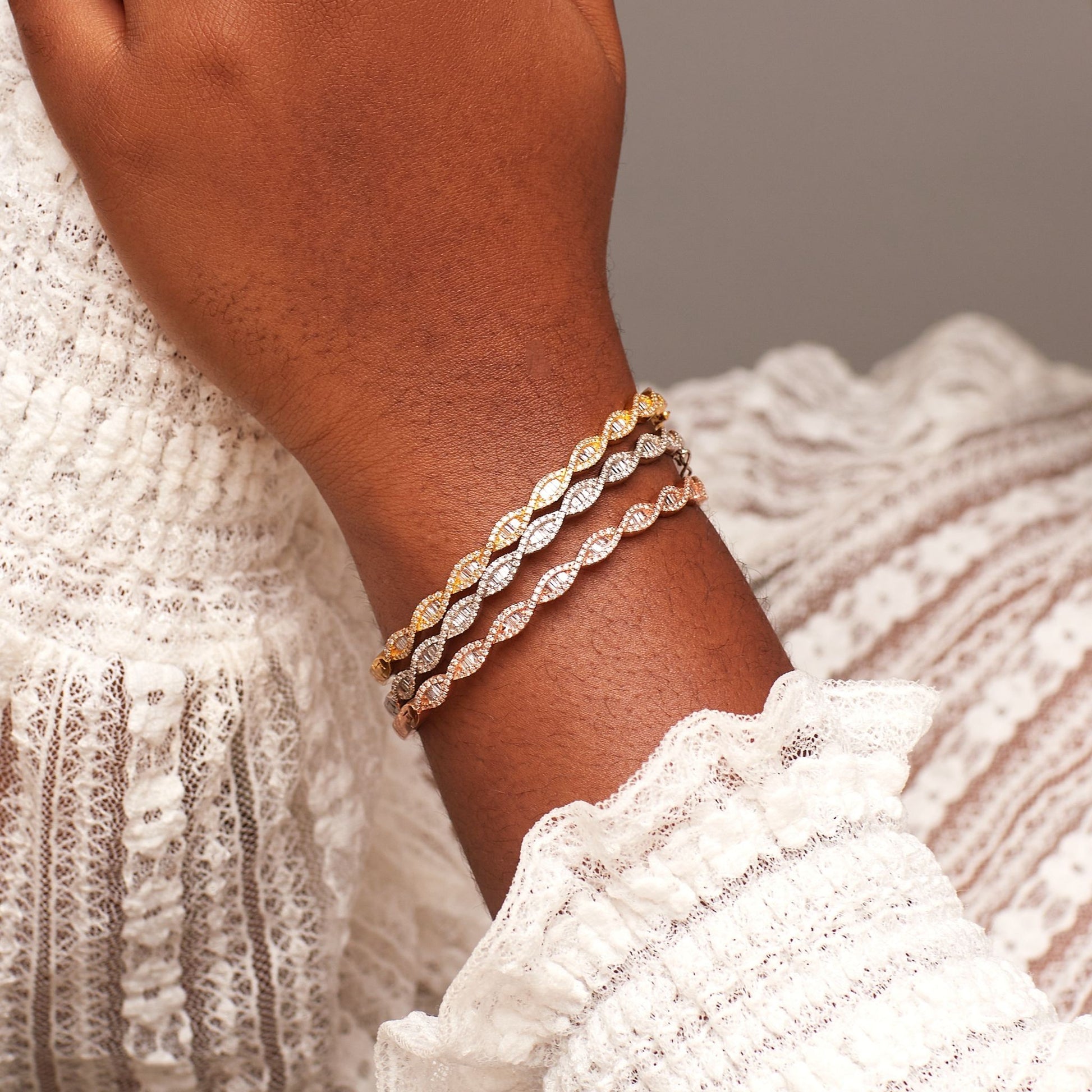 Close-up of a wrist wearing two gold bracelets with a neutral background